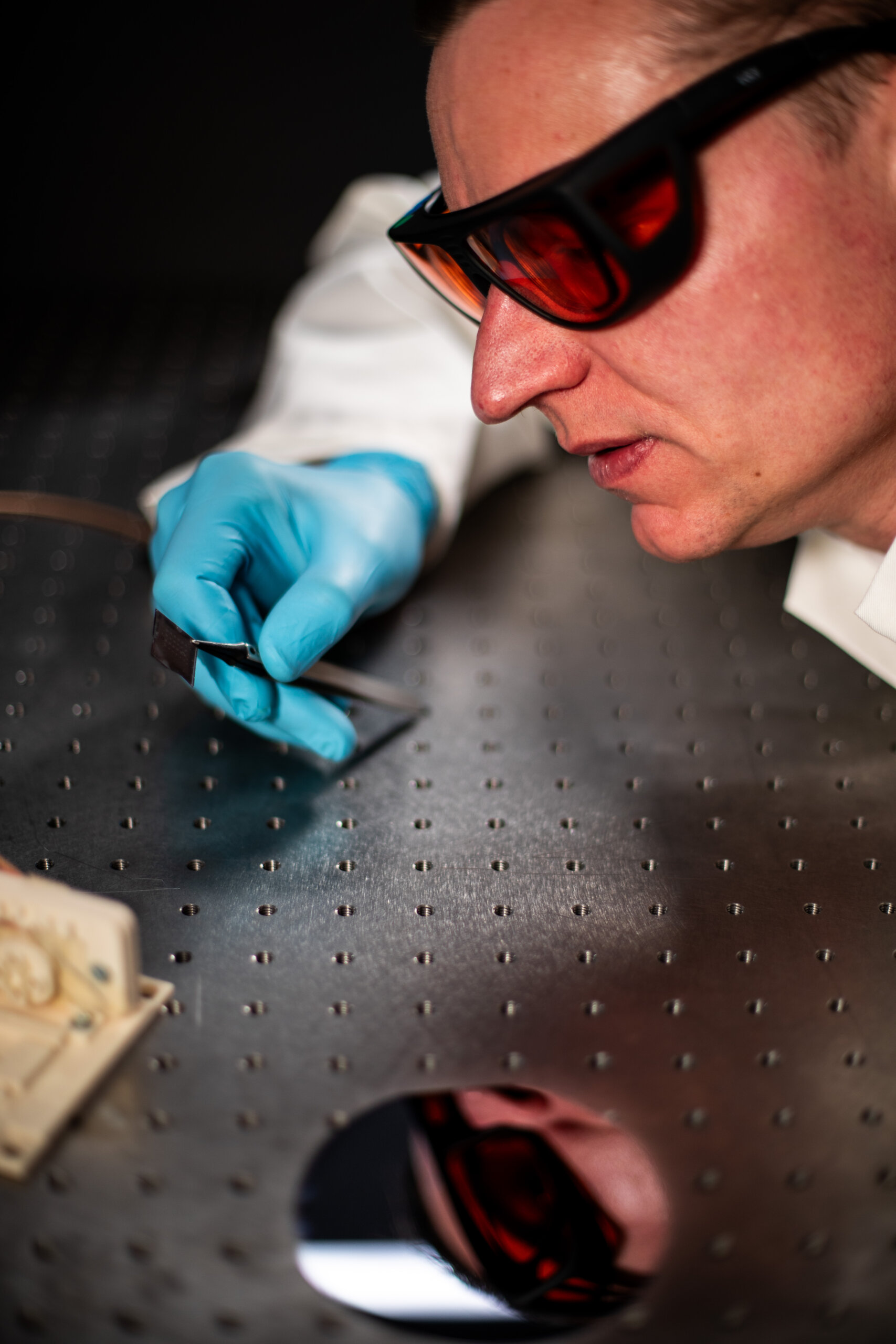 Man (Tim Echtermeyer, PhovIR) examines chip in lap, close up wearing lab attire